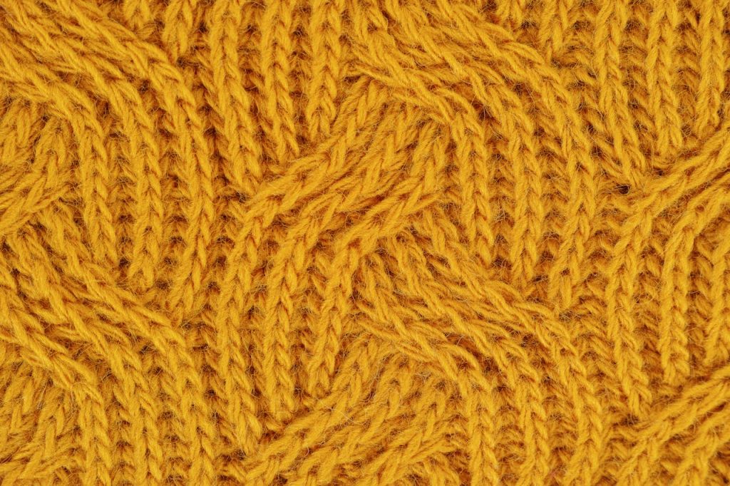 Detailed close-up of a yellow knitted wool pattern, ideal for textile design.